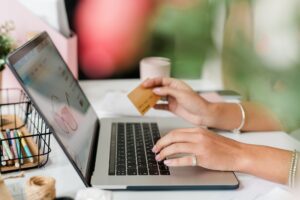 Hands of young woman over laptop keypad ordering eyewear in the internet