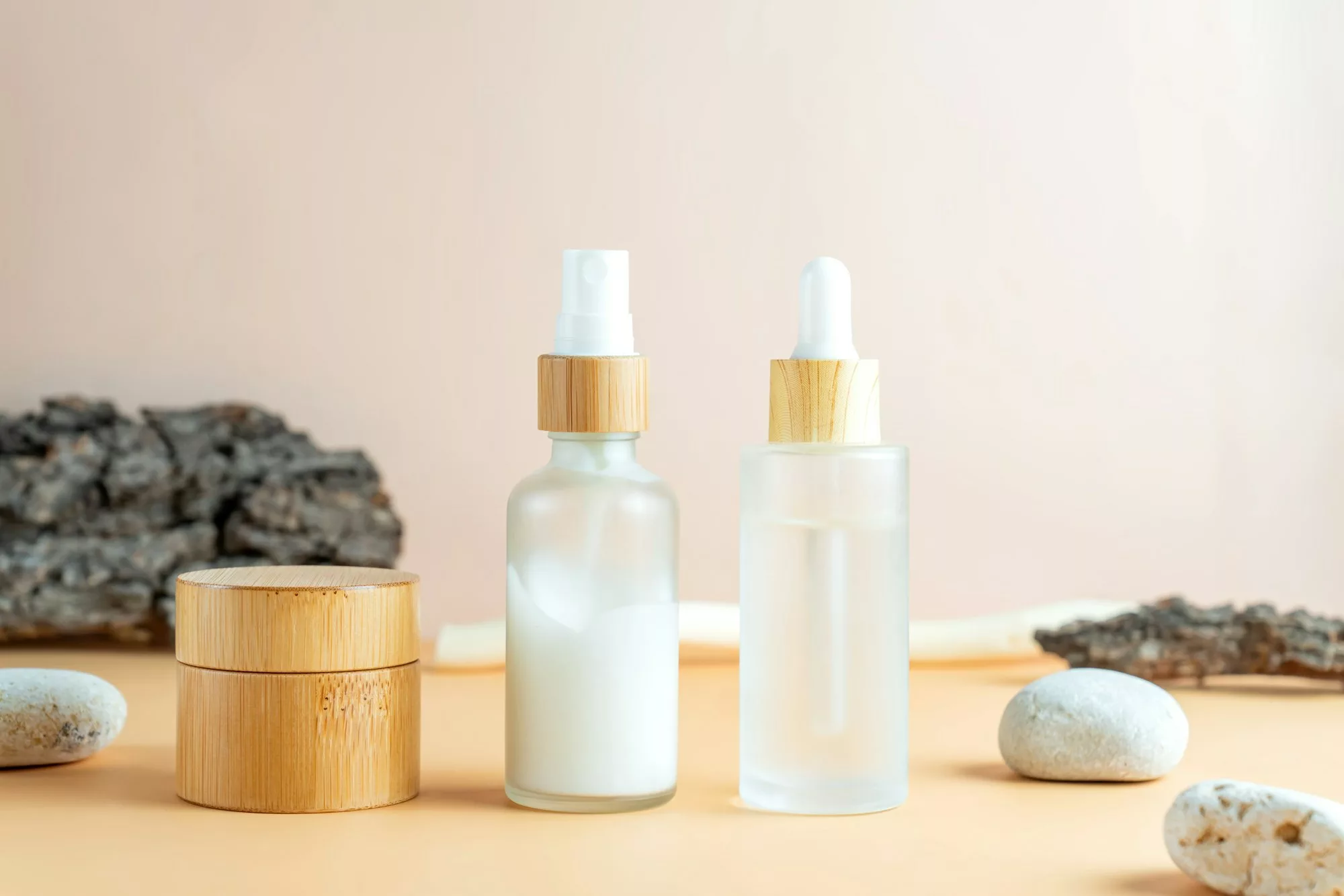 Cosmetic skin care products with tree bark and stones on pastel beige background. Mockup fro design