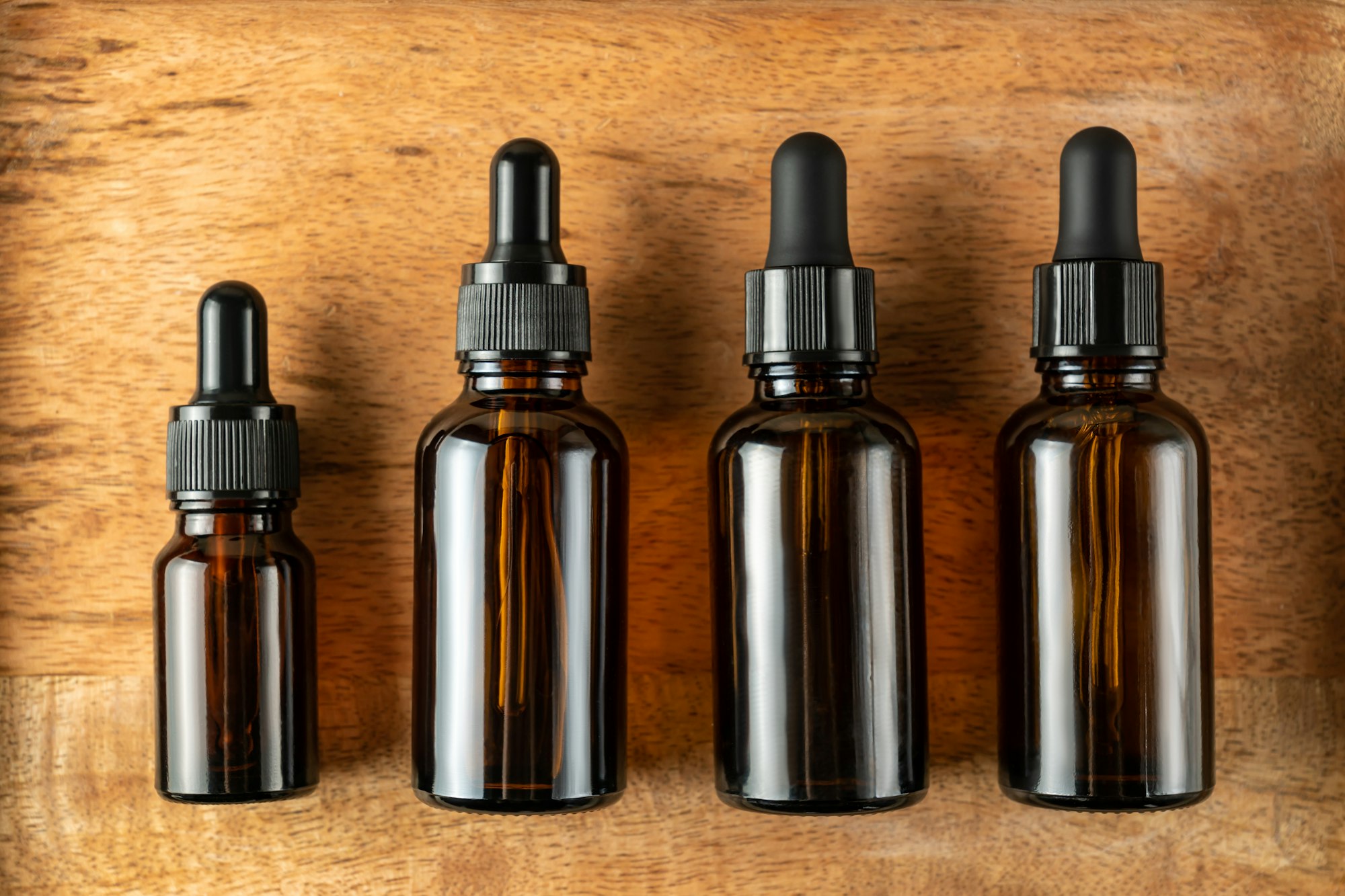 Serum bottles on wooden background. Sustainable lifestyle concept, natural cosmetics. Unbranded Cosm