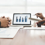 ノートパソコンのグラフを見ながら事業の数字を確認する人たち